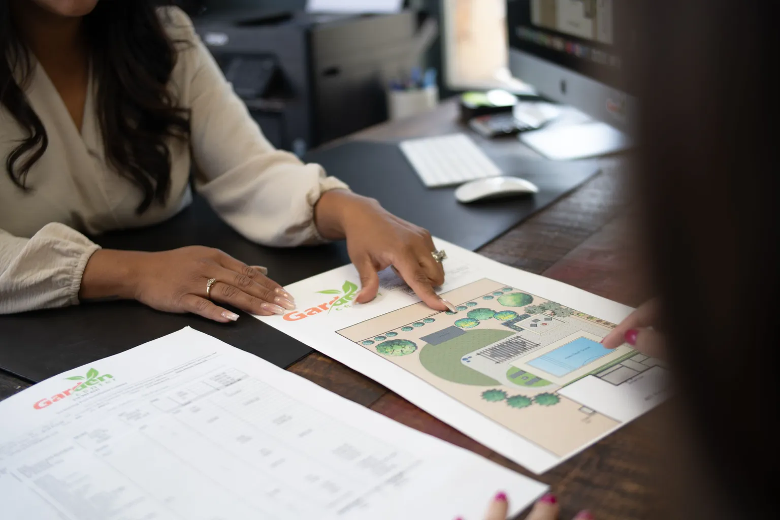 Garden Center of Las Cruces designer and homeowner reviewing a printed backyard plan with a pool and patio