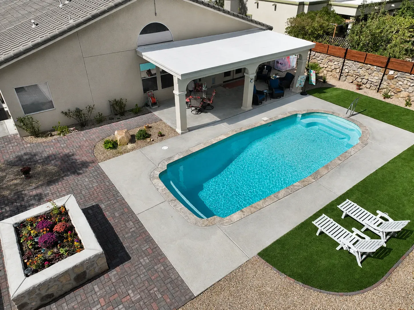 Aerial view of a custom fiberglass pool with paver deck, covered patio, and landscaped backyard in Las Cruces, NM Aerial view of a custom fiberglass pool with paver deck, covered patio, and landscaped backyard in Las Cruces, NM