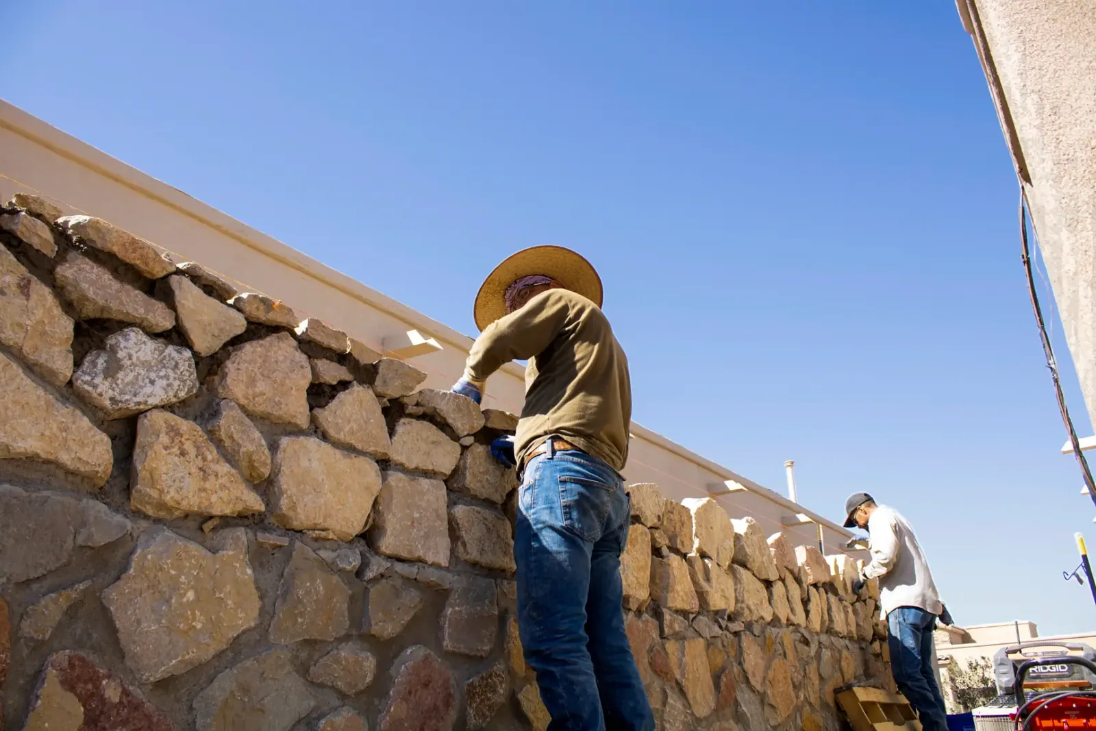 Garden Center of Las Cruces crew in straw hats building a natural stone retaining wall on a Las Cruces, NM job site Garden Center of Las Cruces crew in straw hats building a natural stone retaining wall on a Las Cruces, NM job site