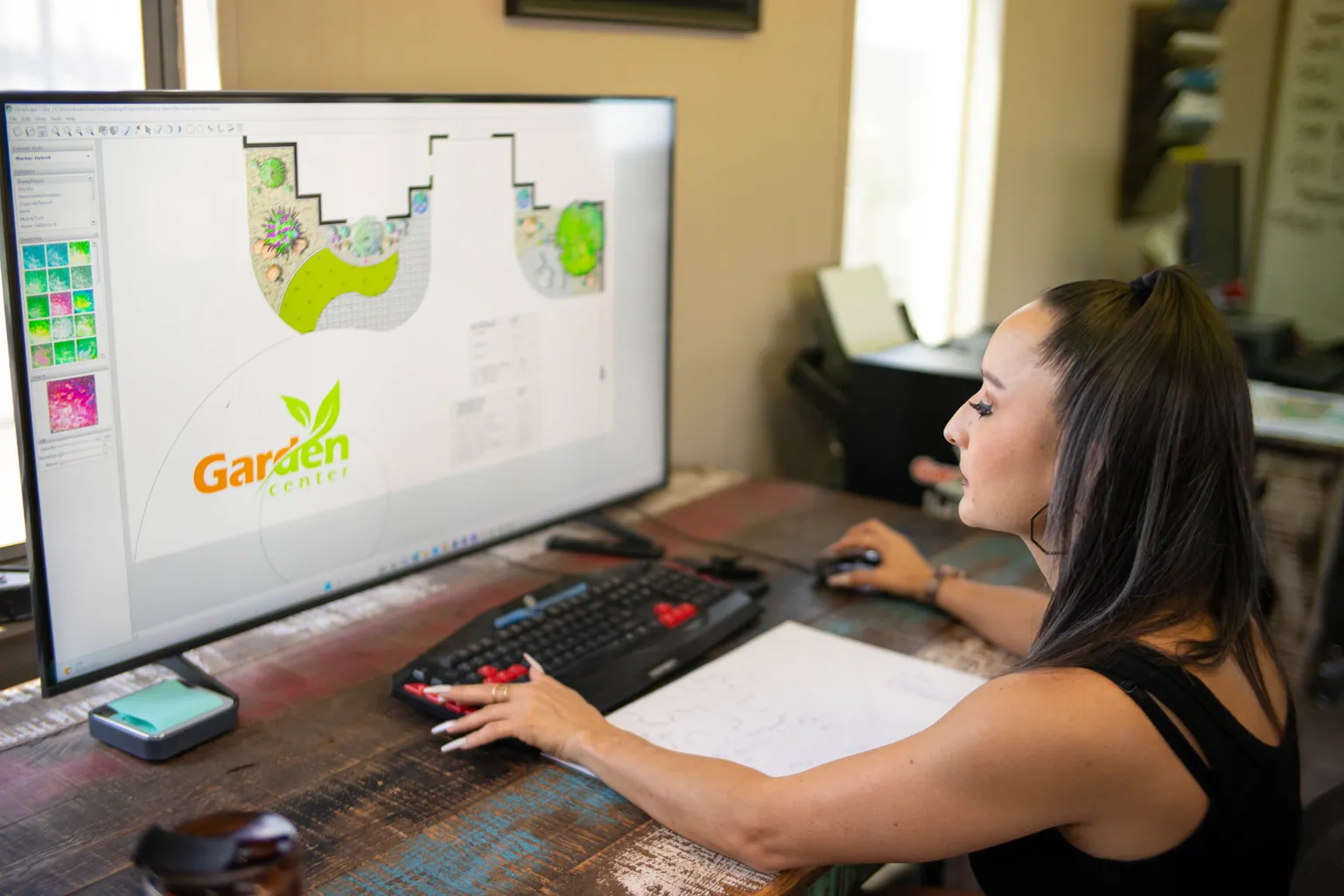 Garden Center of Las Cruces designer reviewing a backyard plan with paver paths and planting beds on a computer screen Garden Center of Las Cruces designer reviewing a backyard plan with paver paths and planting beds on a computer screen